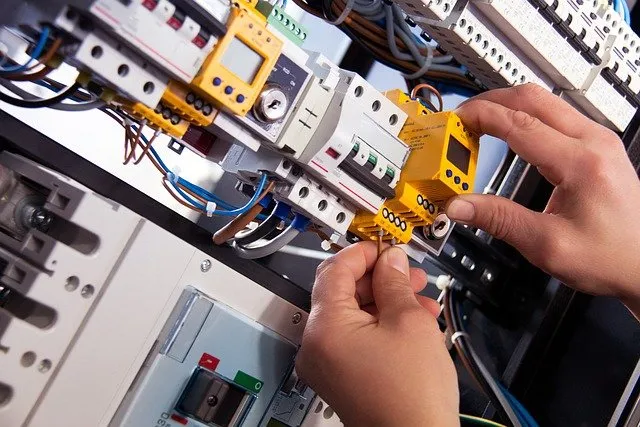 Worker installing a controller in an electrical panel.