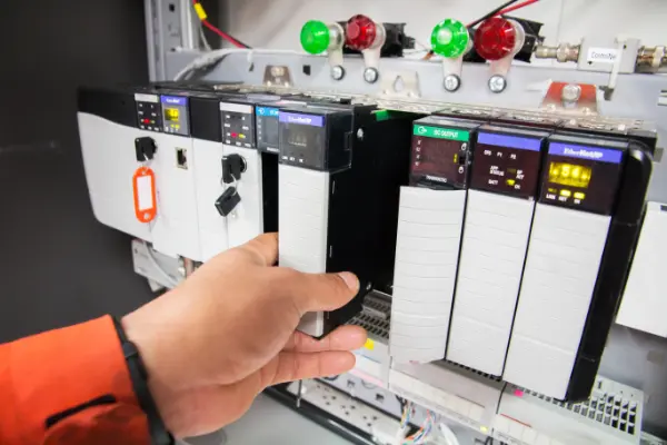 Worker programming a PLC in a factory
